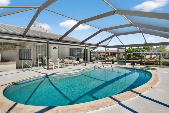 View of pool featuring glass enclosure, a pool with connected hot tub, a patio, and a sunroom
