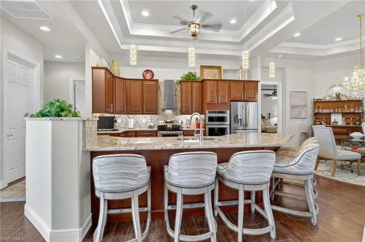 Kitchen with a ceiling fan, decorative backsplash, light stone counters, new decorative light fixtures, and a chandelier