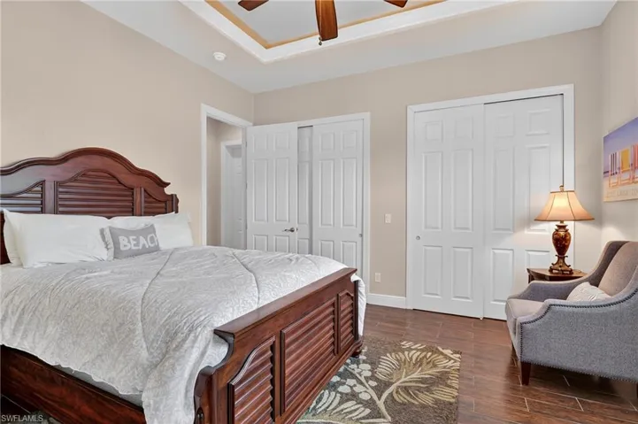 Bedroom featuring dark wood-style tile flooring, two closets, and a ceiling fan