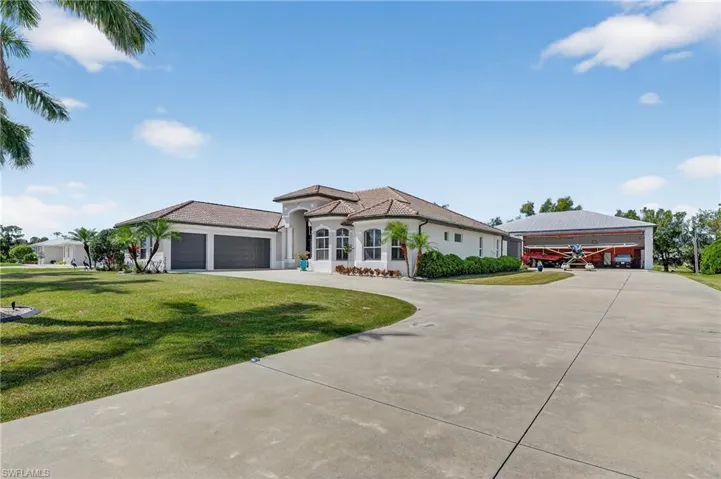 View of front facade featuring newly lit concrete driveway, a front lawn, an attached garage, and hangar