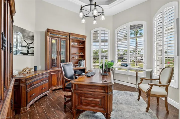 Home office featuring dark wood-style floors and a chandelier
