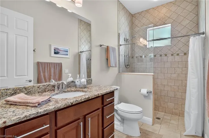 Full bathroom featuring tiled shower, vanity, and light tile patterned flooring