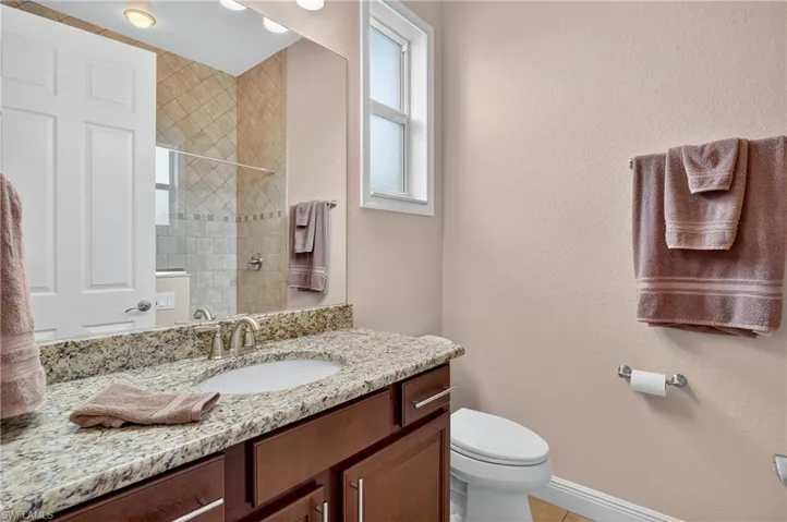 Bathroom featuring vanity, a textured wall, a tile shower, and light tile patterned floors