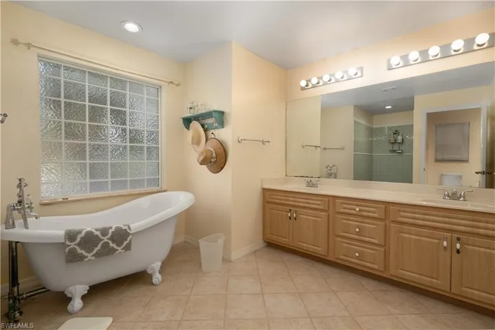 Full bath featuring a freestanding tub, a sink, double vanity, and a stall shower