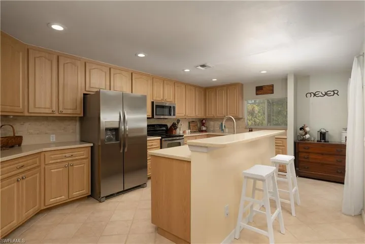 Kitchen with stainless steel appliances, light countertops, visible vents, and backsplash