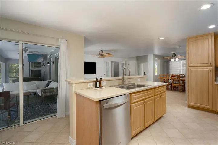 Kitchen with dishwasher, a ceiling fan, light brown cabinets, and a sink