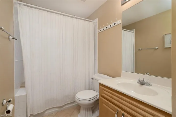 Bathroom with tile patterned flooring, toilet, vanity, and shower / bath combination with curtain