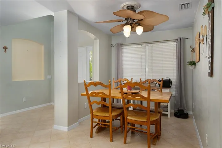 Dining area featuring arched walkways, a ceiling fan, visible vents, and baseboards