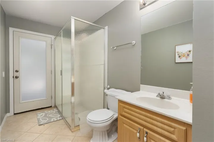 Full bath with a shower stall, toilet, tile patterned flooring, and vanity