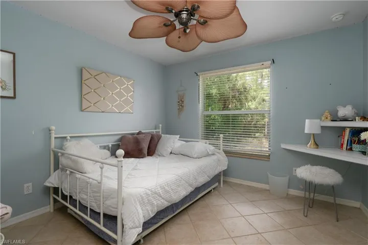 Bedroom with tile patterned floors, baseboards, and a ceiling fan