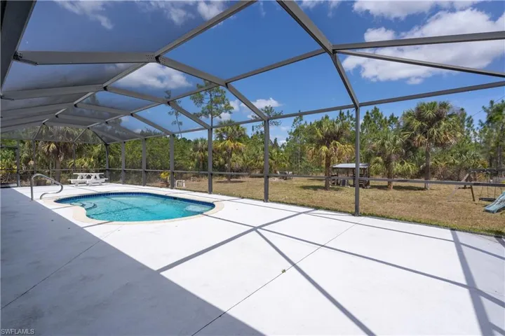 Pool with a patio area and a lawn