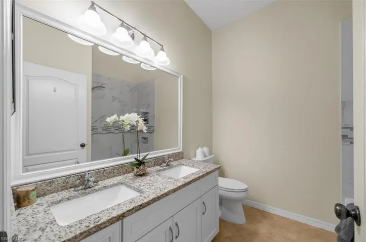 Full bath featuring double vanity and light tile patterned floors