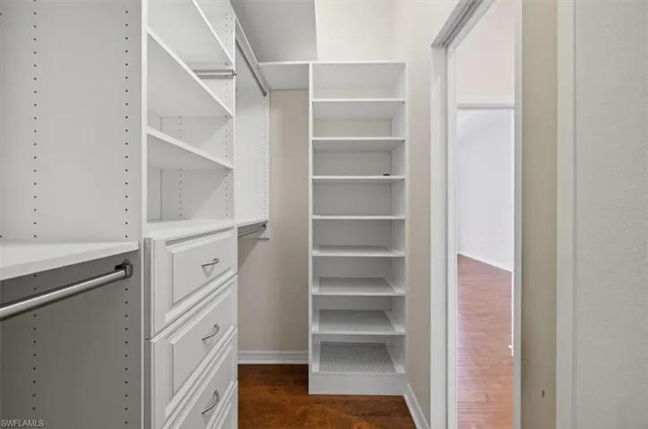 Walk in closet with dark wood-style flooring