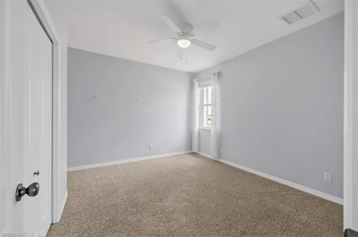 Empty room featuring light carpet and a ceiling fan
