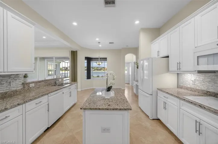 Kitchen with decorative backsplash, a center island, white cabinets, and white appliances