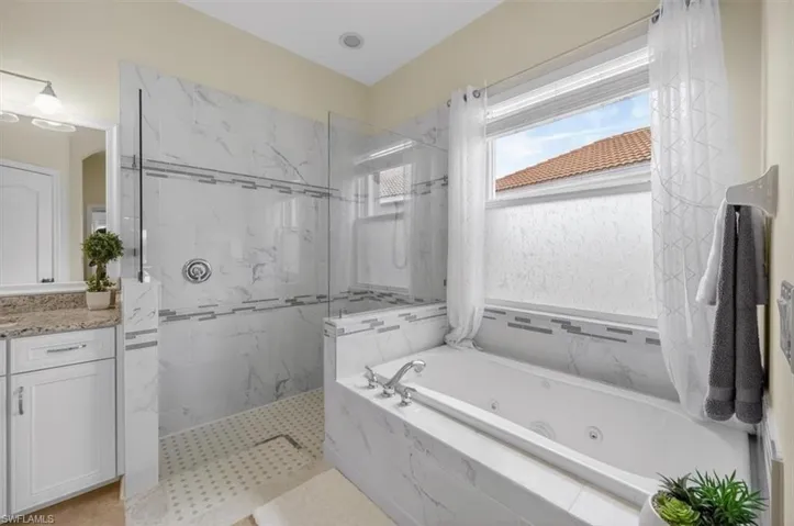 Bathroom featuring a marble finish shower, a whirlpool tub, and vanity