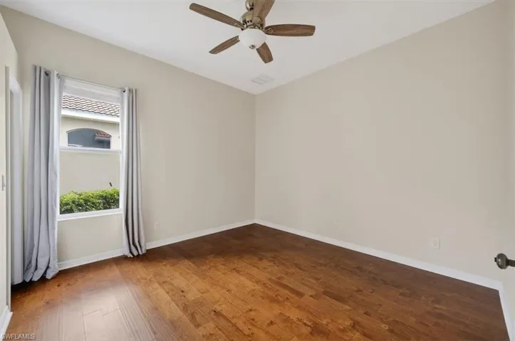 Unfurnished room with dark wood-style floors and a ceiling fan