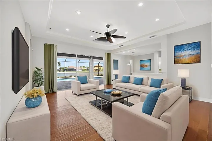 Living area with hardwood / wood-style flooring, ceiling fan, a tray ceiling, and recessed lighting