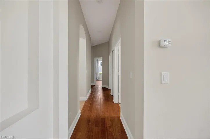 Hall with baseboards and dark wood-style floors