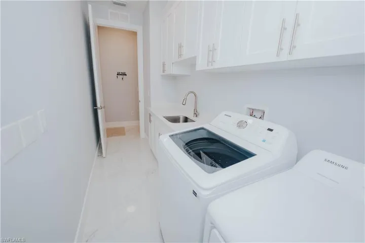 Clothes washing area featuring cabinets, independent washer and dryer, and sink