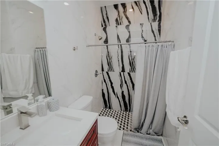 Mother-in-law suit Bathroom with tile walls, a shower with curtain, toilet, and vanity