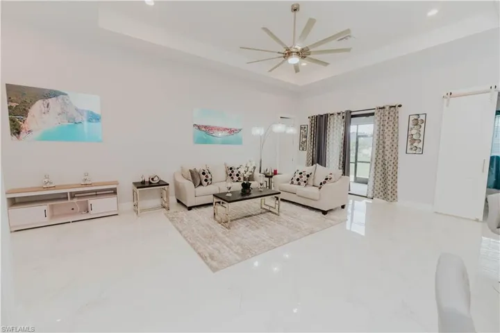 Living room featuring a barn door, a tray ceiling, and ceiling fan