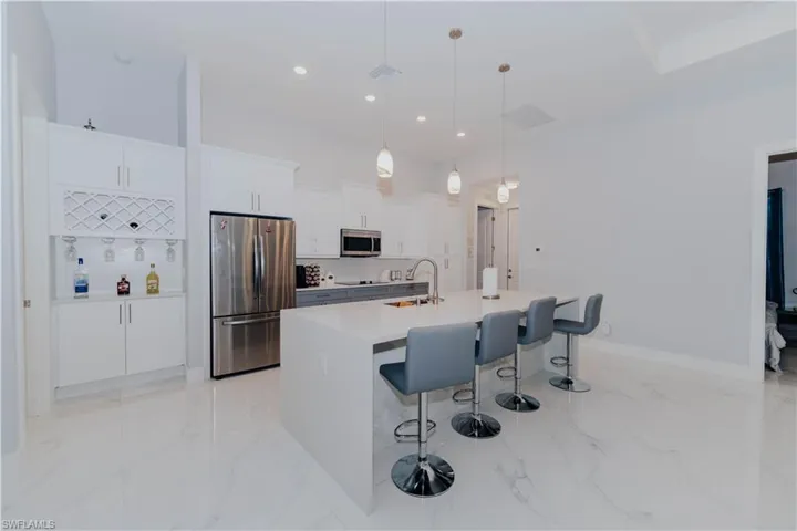 Kitchen featuring a kitchen island with sink, pendant lighting, white cabinetry, stainless steel appliances, and sink