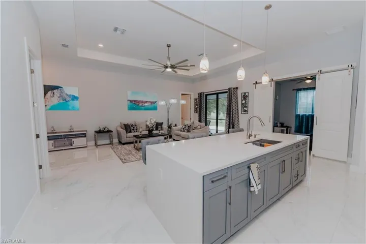 Kitchen with a raised ceiling, an island with sink, sink, and a barn door