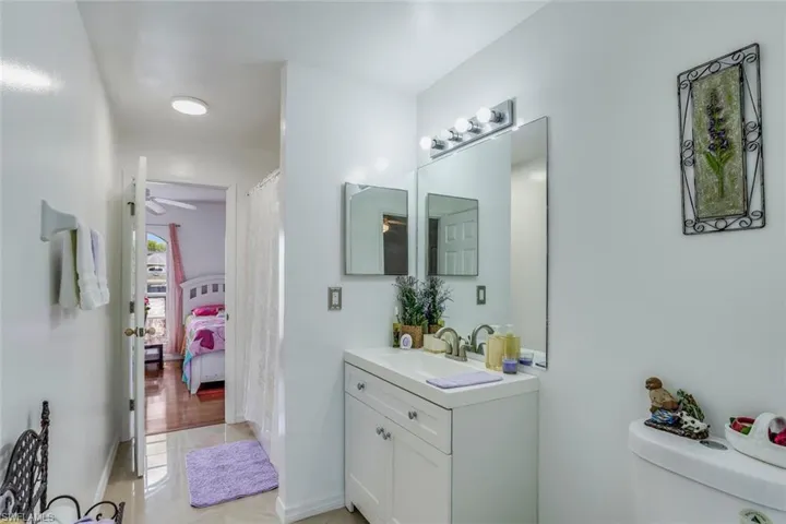 Ensuite bathroom with vanity, a shower with shower curtain, and a ceiling fan