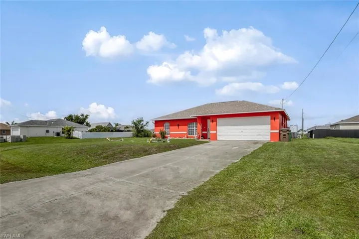 View of front of home with a front yard, concrete driveway, and an attached garage