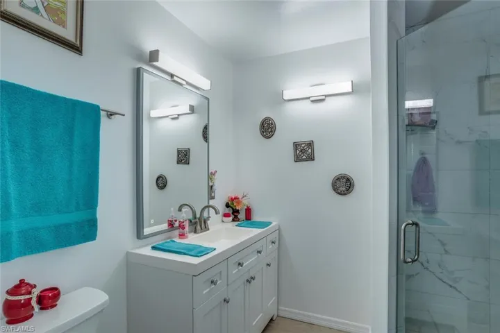 Bathroom featuring a marble finish shower and vanity