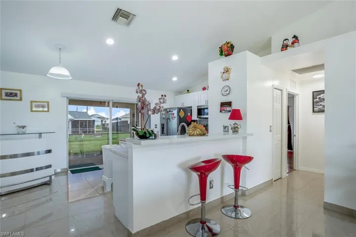 Kitchen with a kitchen breakfast bar, a peninsula, stainless steel appliances, lofted ceiling, and hanging light fixtures