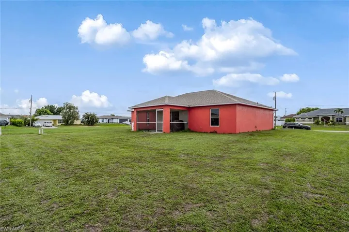 Back of house with a yard, stucco siding, and a sunroom