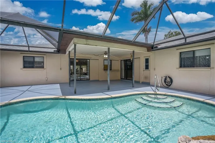 View of swimming pool featuring ceiling fan, a patio, and glass enclosure