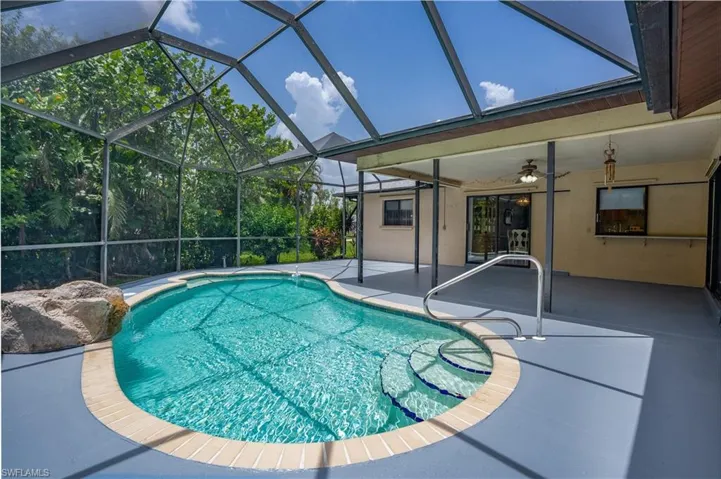 View of swimming pool with a lanai, ceiling fan, and a patio area