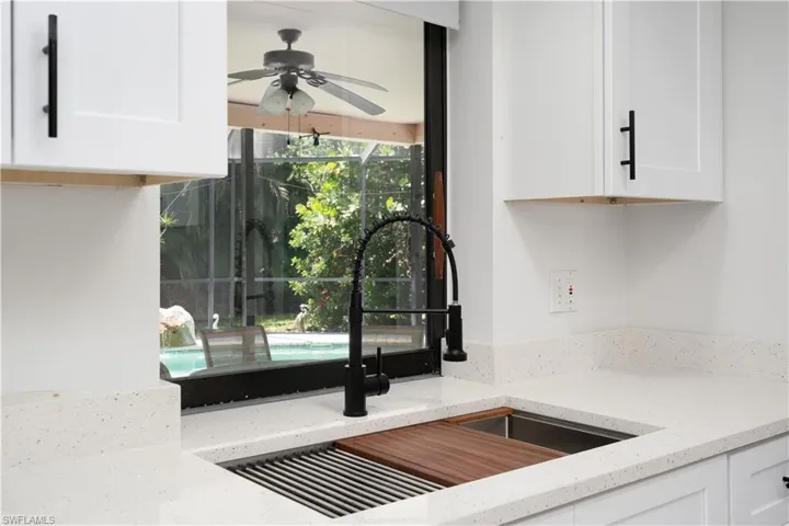 Kitchen featuring white cabinetry, sink, ceiling fan, and light stone countertops