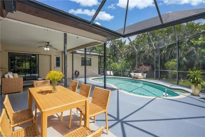 Virtually Staged View of swimming pool featuring ceiling fan, a patio area, and glass enclosure