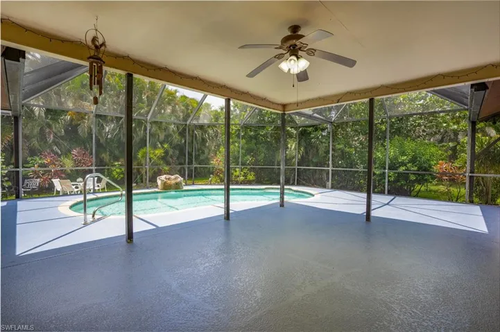 View of swimming pool with glass enclosure and a patio area