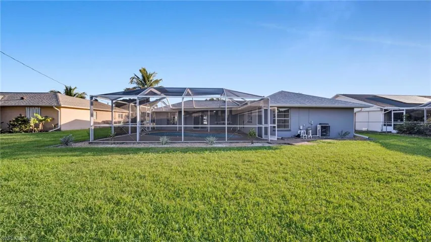 Rear view of house with glass enclosure, a pool, a sunroom, and a yard