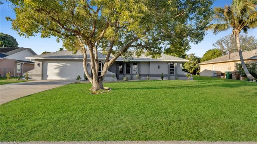 Ranch-style house featuring stucco siding, a front yard, driveway, and an attached garage