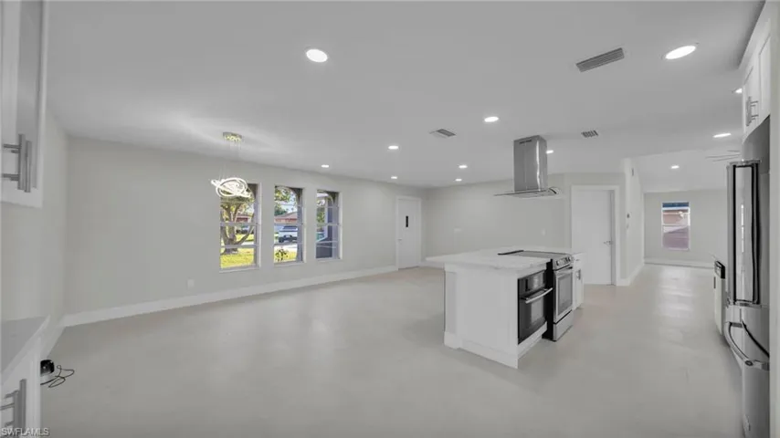 Kitchen with white cabinetry, open floor plan, island range hood, a kitchen island, and stainless steel appliances