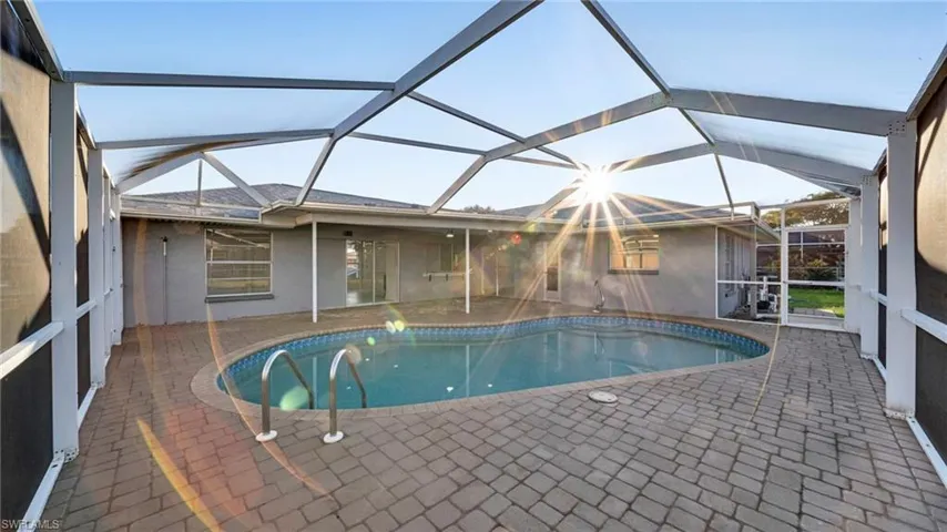 Outdoor pool featuring a sunroom, a patio, and a lanai