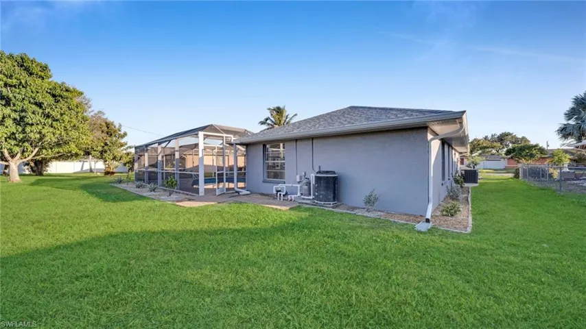 Rear view of house with a sunroom, glass enclosure, a fenced backyard, stucco siding, and roof with shingles