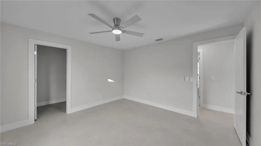 Unfurnished bedroom with ceiling fan, a spacious closet, and light tile patterned floors