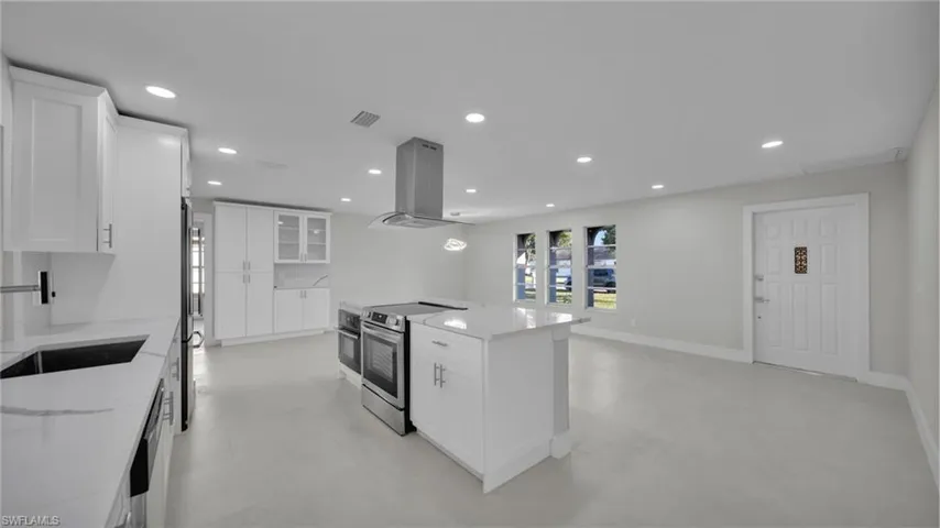 Kitchen with white cabinets, glass fronted cabinets, stainless steel appliances, recessed lighting, and light stone countertops