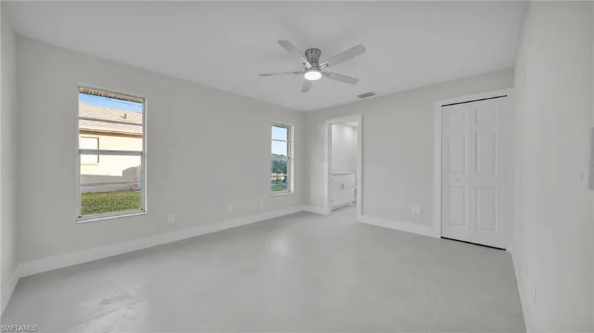 Unfurnished bedroom featuring ensuite bath, a ceiling fan, and a closet