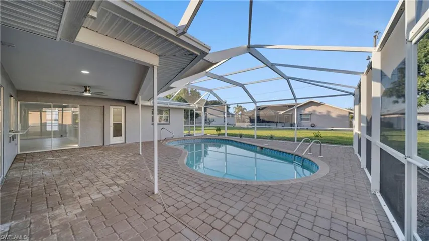 Swimming pool with a patio, a sunroom, a lanai, a yard, and a residential view
