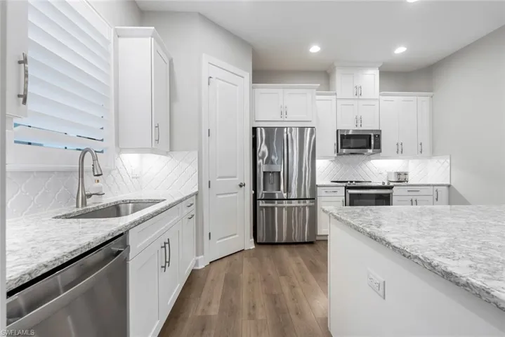 Kitchen featuring white cabinets, stainless steel appliances, dark wood-type flooring, and sink