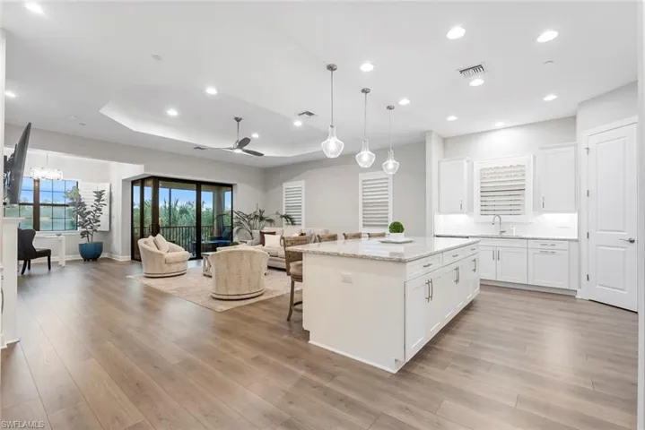 Kitchen featuring a breakfast bar, light wood-type flooring, pendant lighting, white cabinetry, and a kitchen island