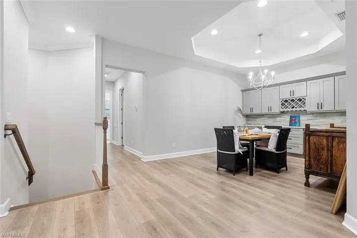 Dining room featuring light wood-type flooring, a tray ceiling, and a chandelier